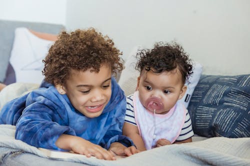 Black brothers playing on soft cozy bed