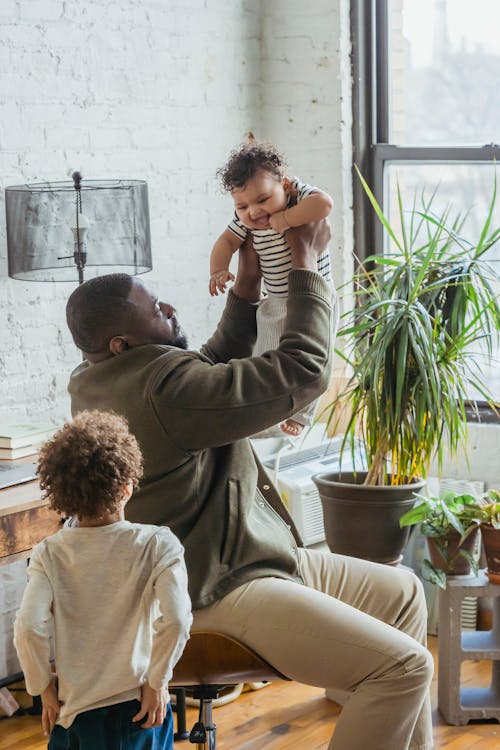 Bald African American father enjoying weekend with adorable little toddler and son at home