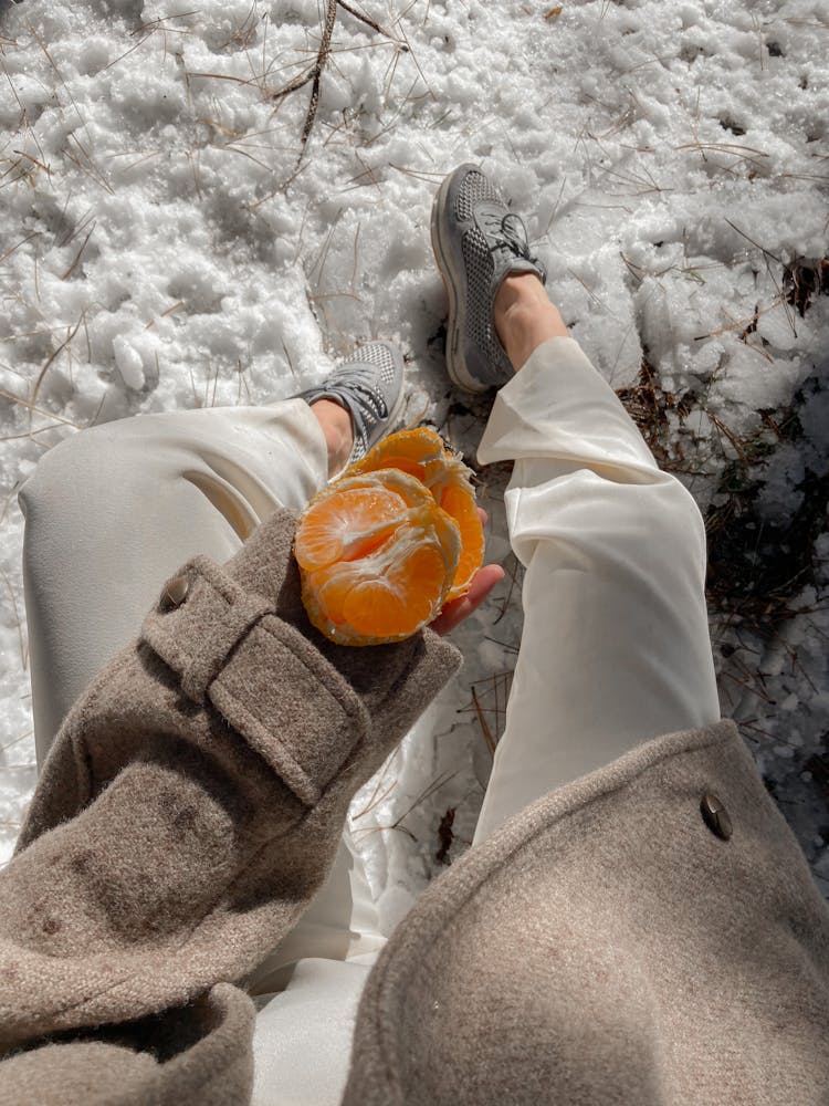 Crop Woman With Tangerine In Winter Park