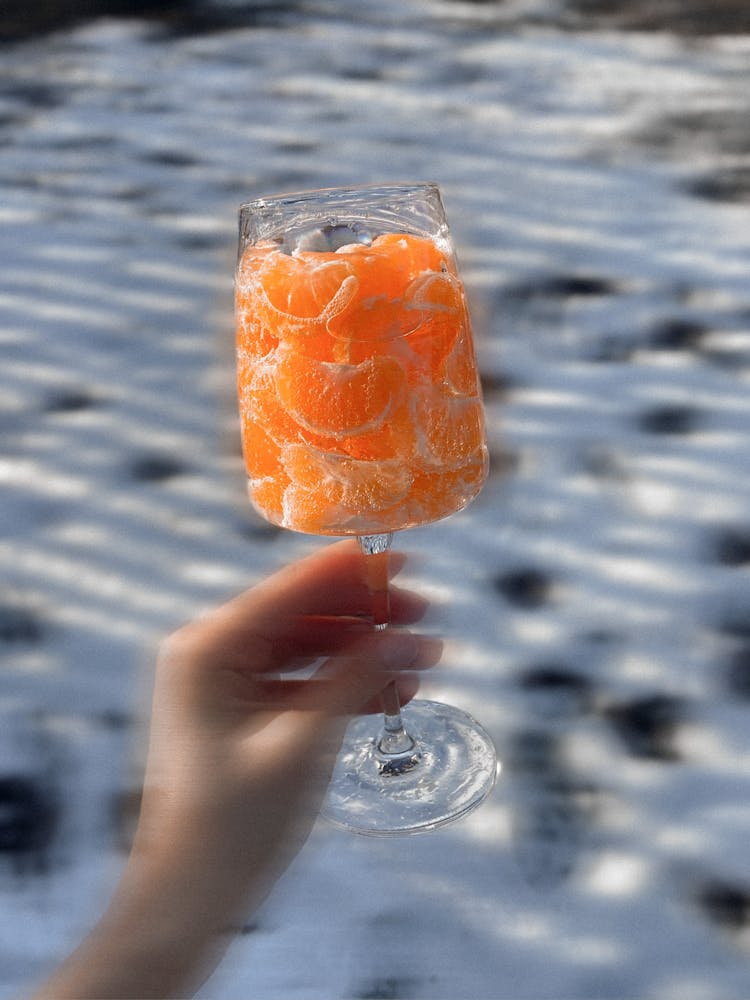 Crop Person With Glass Of Tangerines In Nature