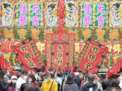 Traditional Chinese festival in front of large colorful signboard with flags
