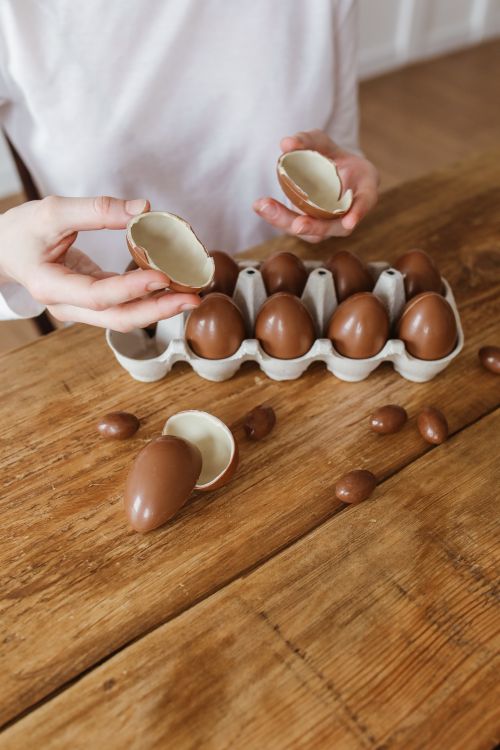 Free A carton filled with chocolate eggs on a rustic wooden table, partly opened. Stock Photo
