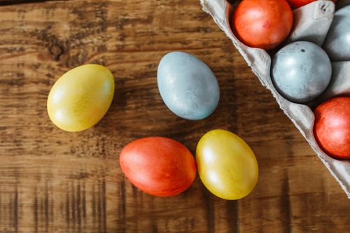 Free Vibrant Easter eggs displayed on a wooden table, perfect for festive decor. Stock Photo