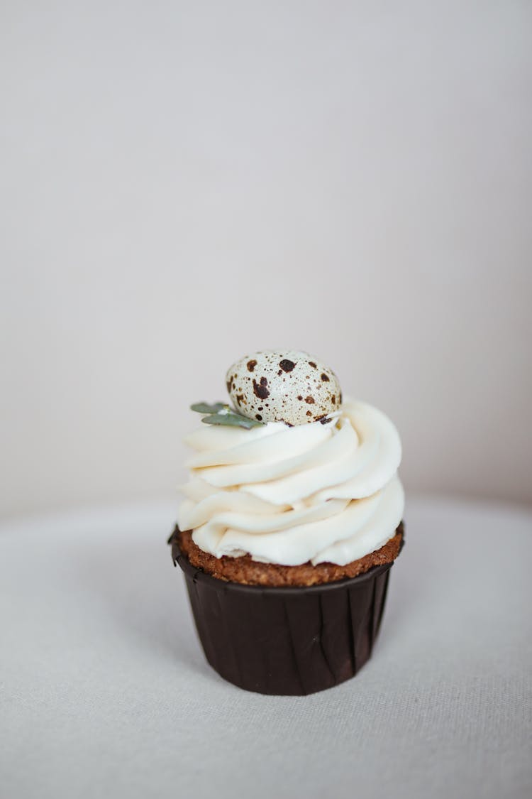 A Cupcake With Icing Cream And Quail Egg Toppings