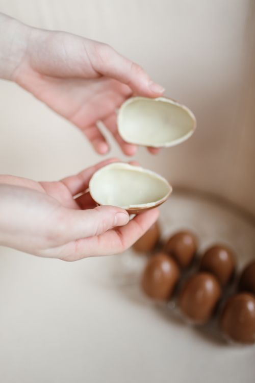 Free A close-up image of hands holding two halves of a chocolate egg, perfect for Easter themes. Stock Photo