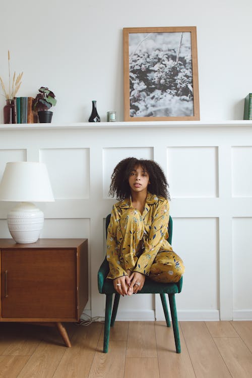 Free Woman in Yellow Pajamas Sitting on the Chair in the Living Room Stock Photo