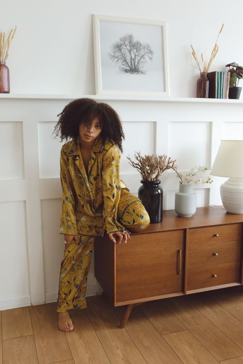 Free African American woman in stylish pajamas posing indoors with home decor elements. Stock Photo