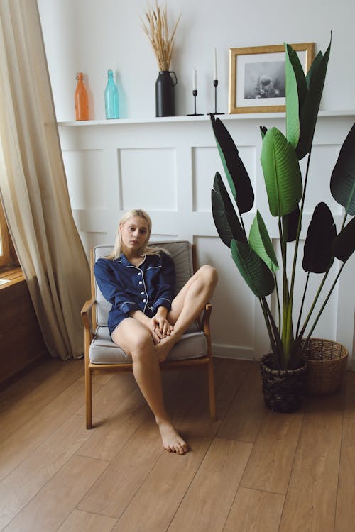 Woman in her Blue Pajama Sitting on a Brown Wooden Armchair