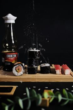 Appetizing sushi rolls and crab sticks on a wooden tray with soy sauce.