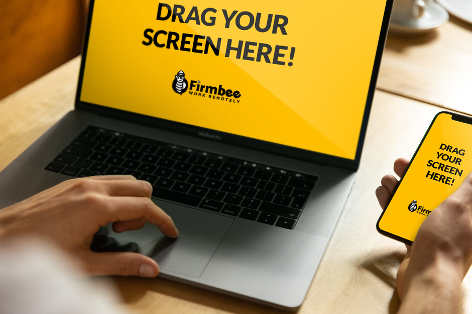 Close-up of hands using a laptop and smartphone displaying Firmbee's remote work interface.
