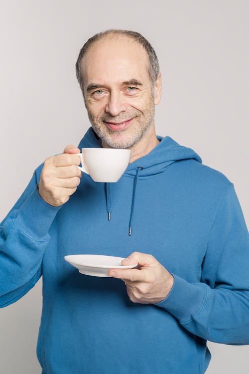 Man in Blue Hoodie Holding White Ceramic Mug