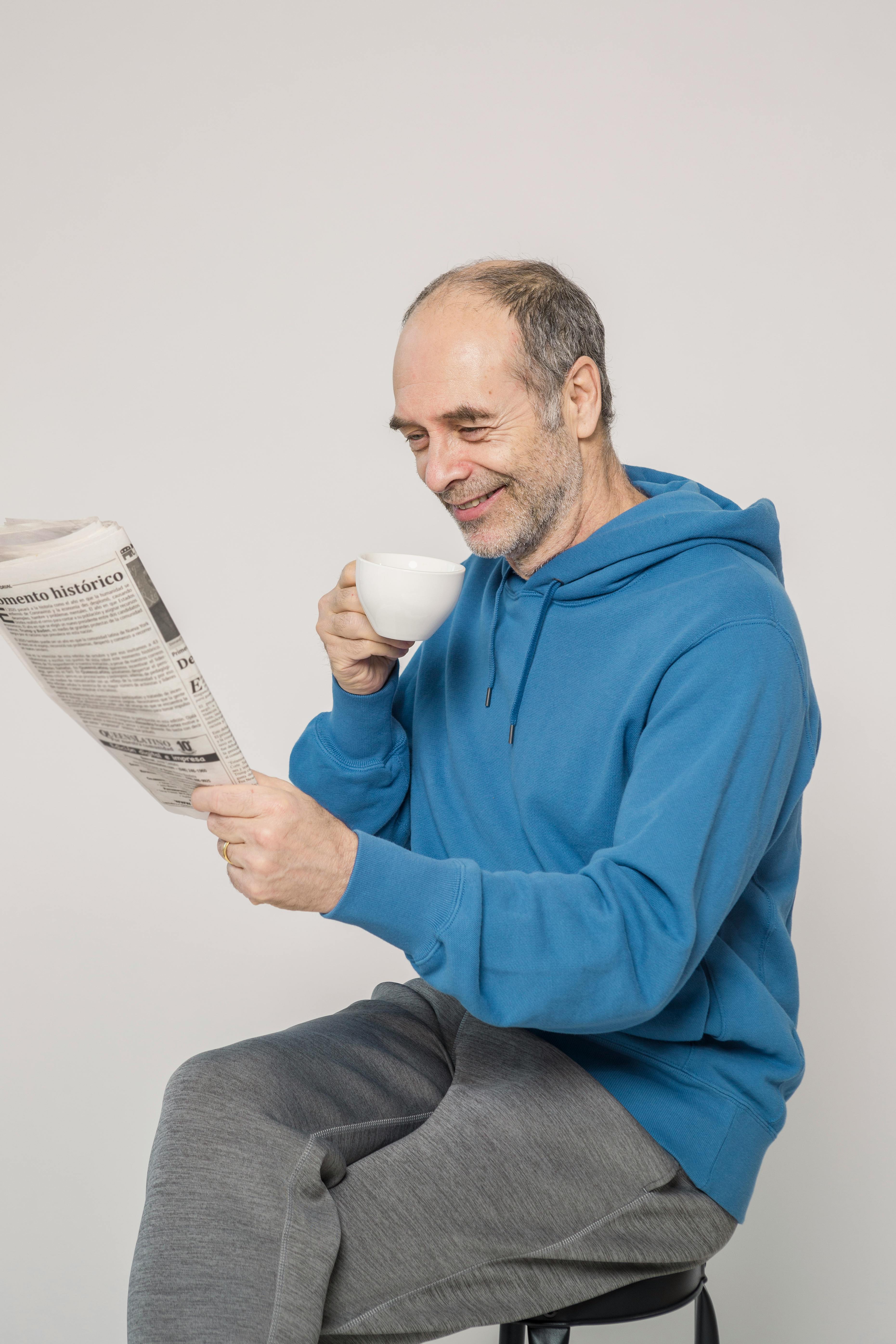 man in blue hoodie drinking from white ceramic mug