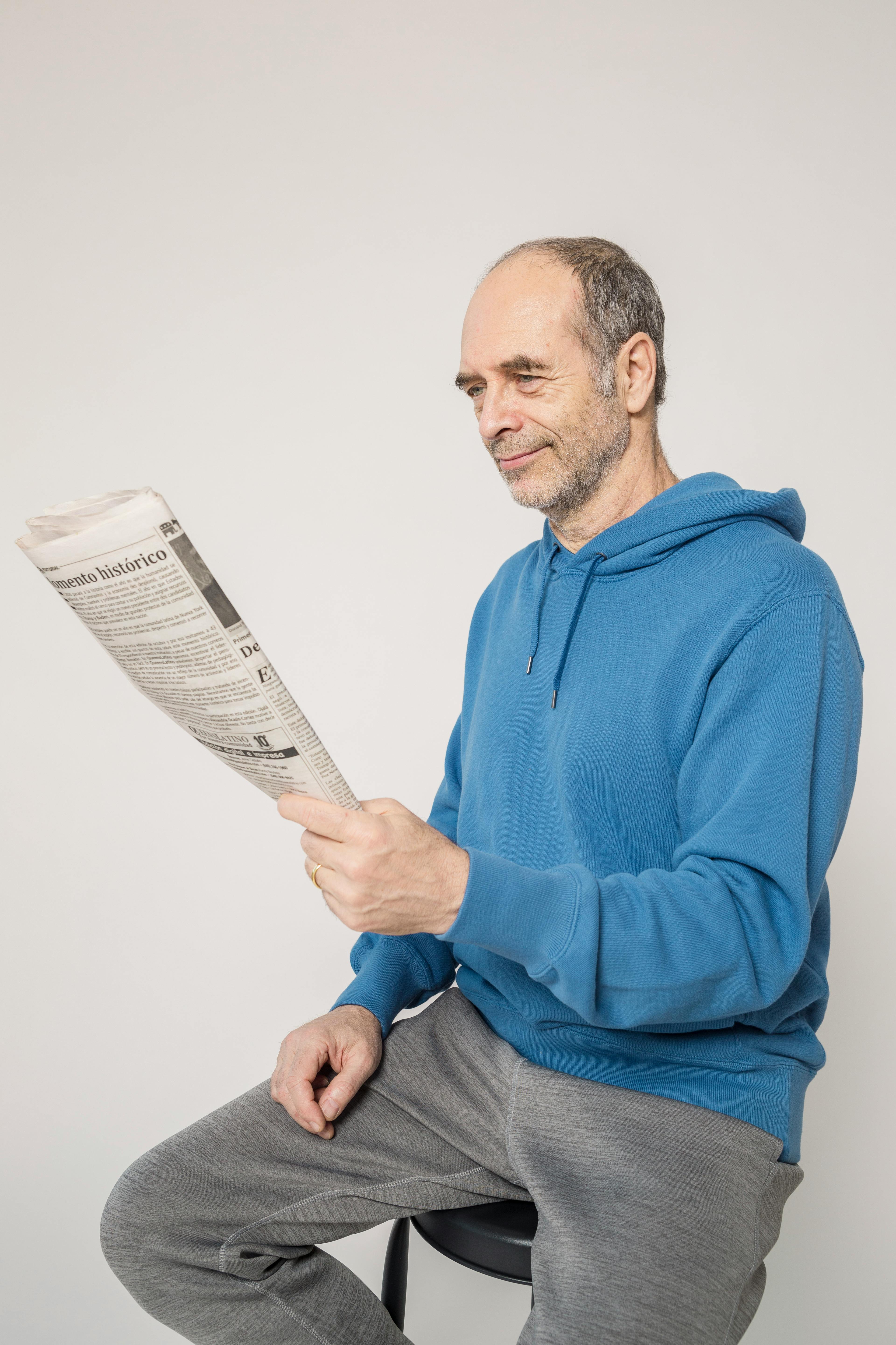 man in blue hoodie holding newspaper