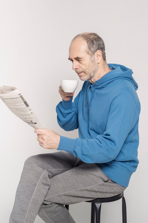 Free Man in Blue Hoodie Reading Newspaper Stock Photo