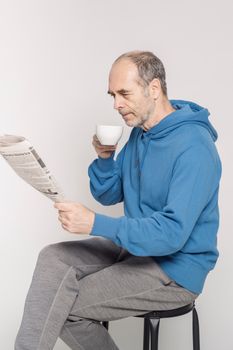 Senior man enjoying a relaxing moment with coffee and newspaper indoors.