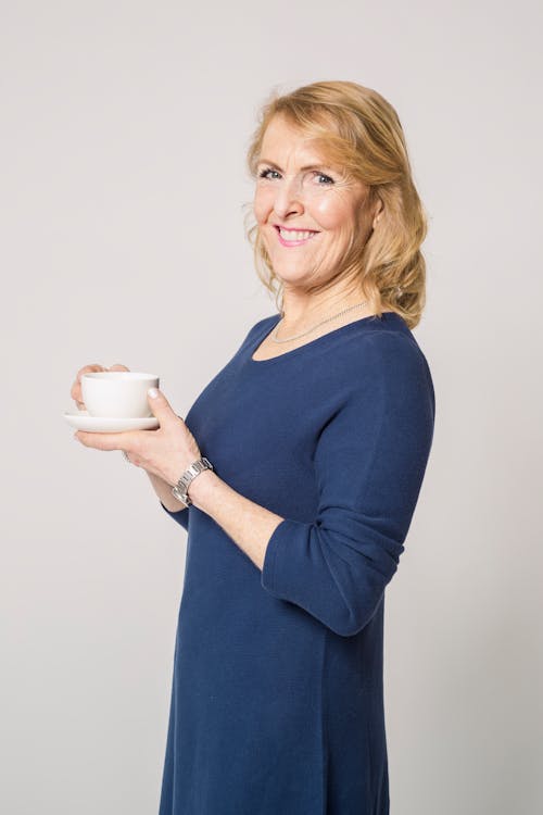 Free Woman in Blue Long Sleeve Dress Holding White Ceramic Mug Stock Photo