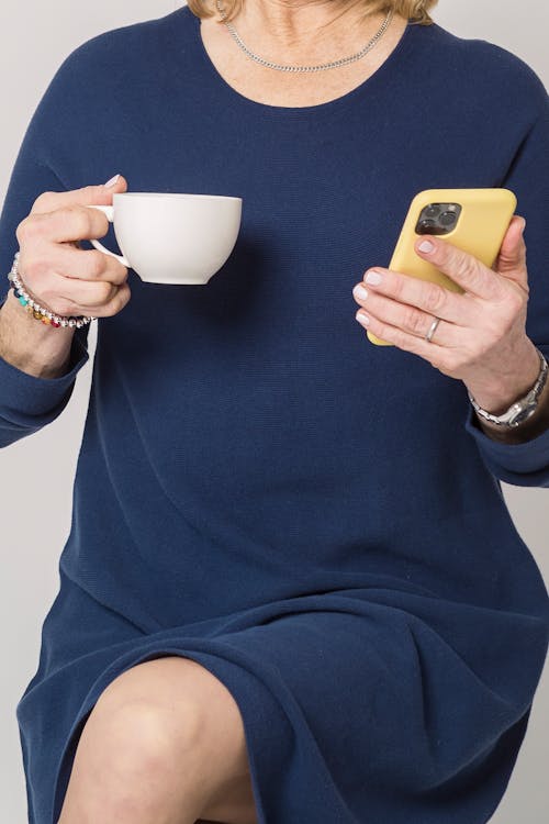 Woman in Blue Long Sleeve Dress Holding White Ceramic Mug