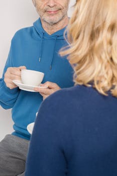 A candid moment capturing an elderly couple enjoying tea together indoors, embracing love and companionship.