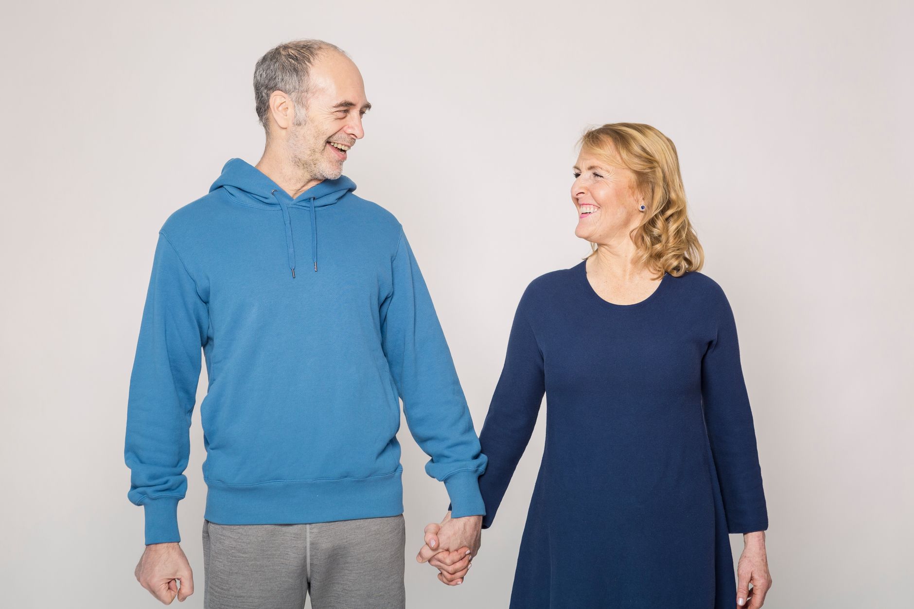 Elderly couple smiling and holding hands, showcasing love and happiness indoors.