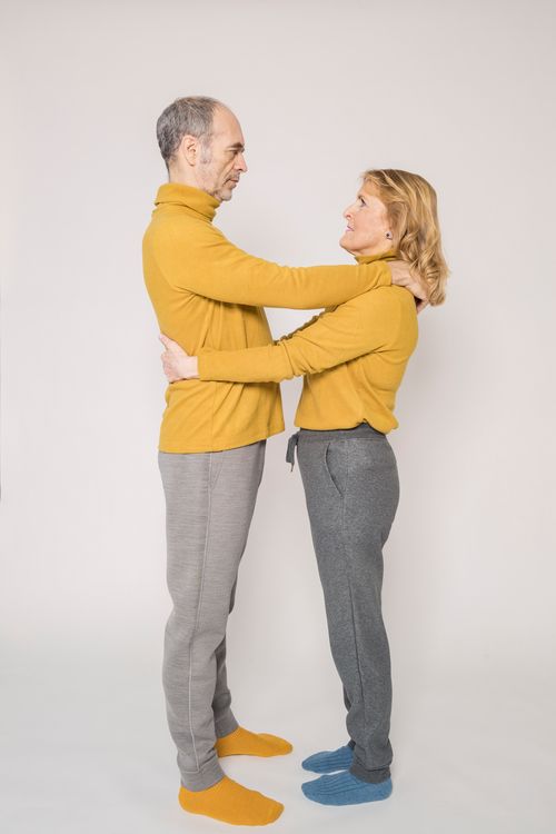 Free Elderly couple in yellow sweaters embracing indoors, showcasing love and togetherness. Stock Photo