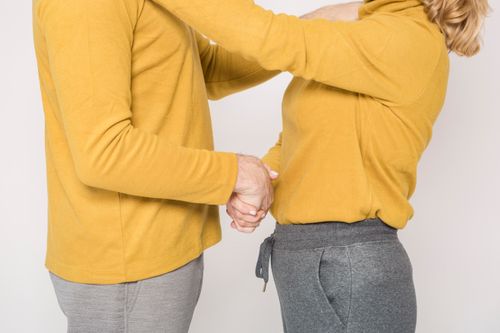 Free Elderly couple indoors, wearing yellow clothing, expressing love and togetherness. Stock Photo