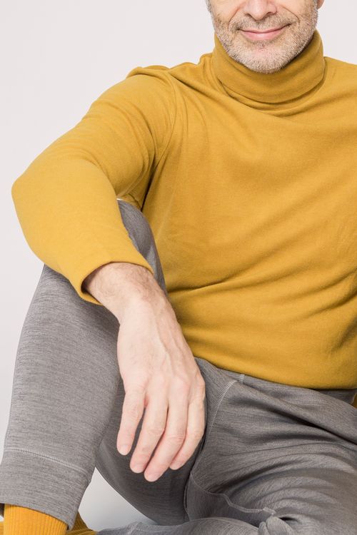Free Portrait of a smiling man in a yellow turtleneck and gray pants. Stock Photo
