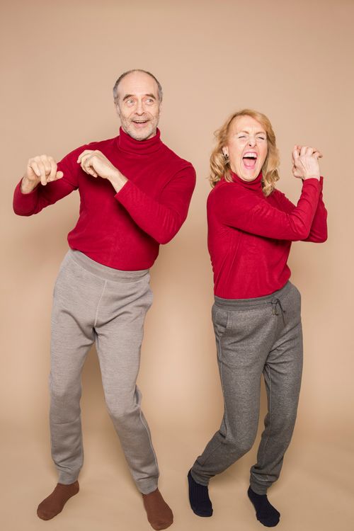 Free Lively portrait of a cheerful senior couple dancing in red sweaters, exuding happiness and fun. Stock Photo