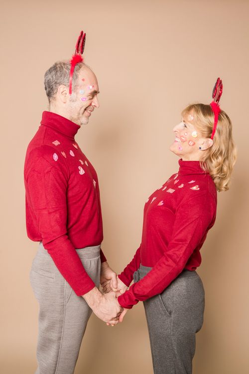 Free Elderly couple in red sweaters with playful stickers, holding hands, and smiling. Stock Photo