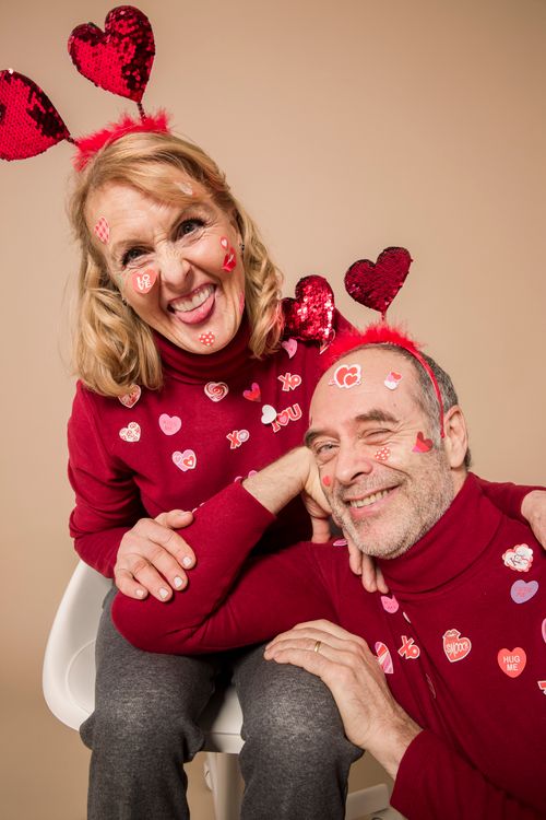 Free Adorable senior couple in red attire with heart stickers, laughing and celebrating Valentine's Day. Stock Photo