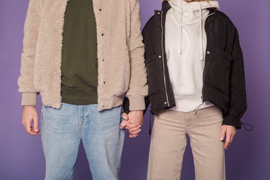 Stylish couple in casual attire holding hands, illustrating urban winter fashion.