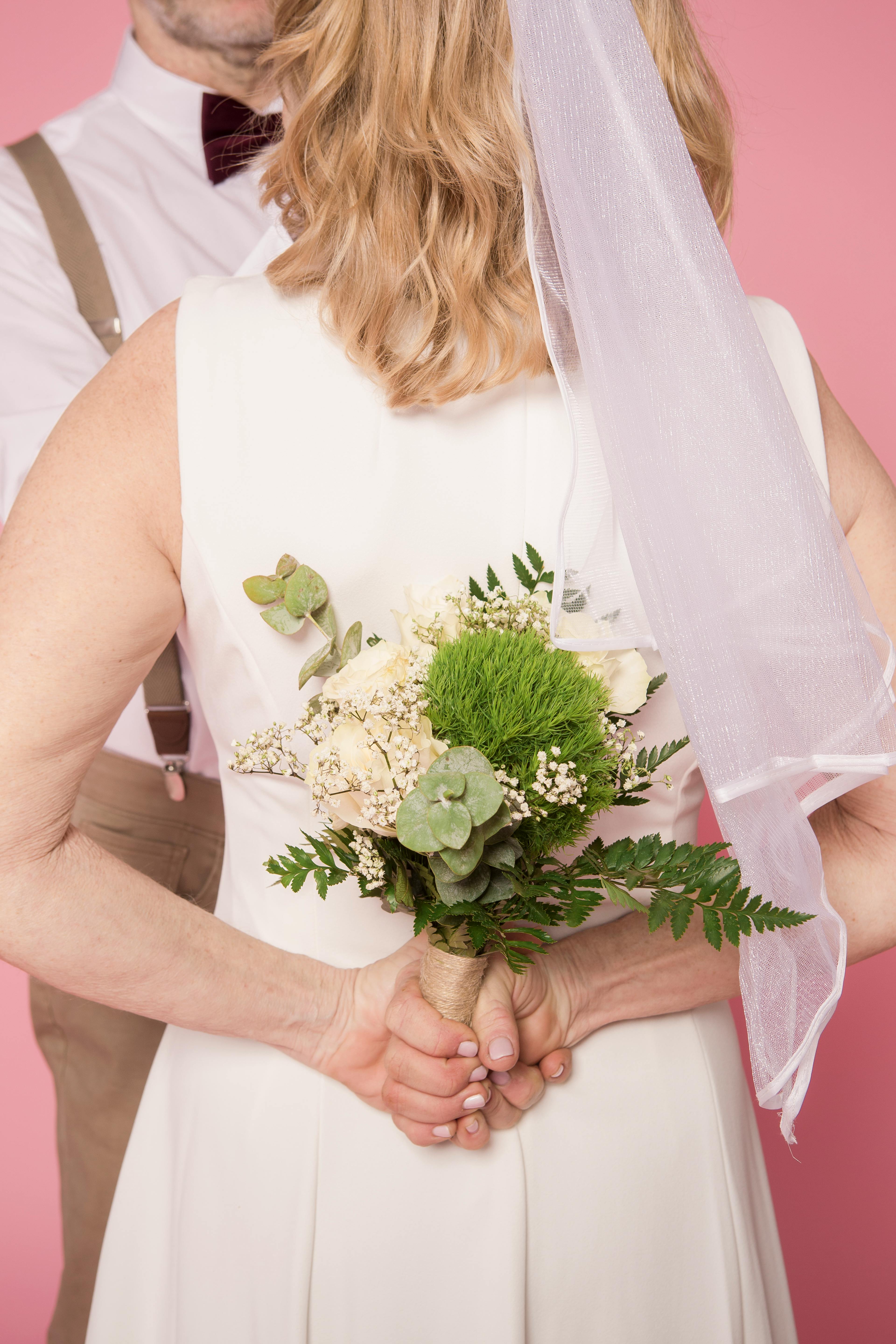 woman in white sleeveless dress holding white flower bouquet