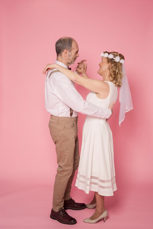 Man in White Dress Shirt and Brown Pants Dancing with Woman in White Dress