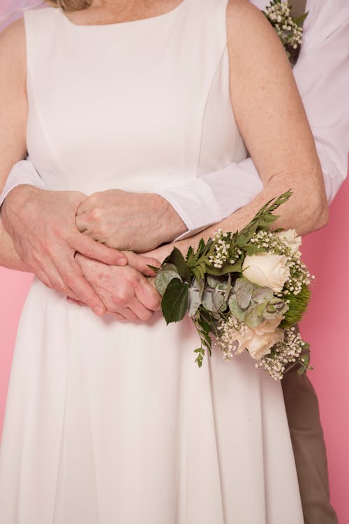 Woman in White Sleeveless Dress Holding White Flower Bouquet