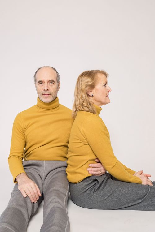 Free Senior couple in yellow sweaters sitting together, symbolizing love and togetherness. Stock Photo