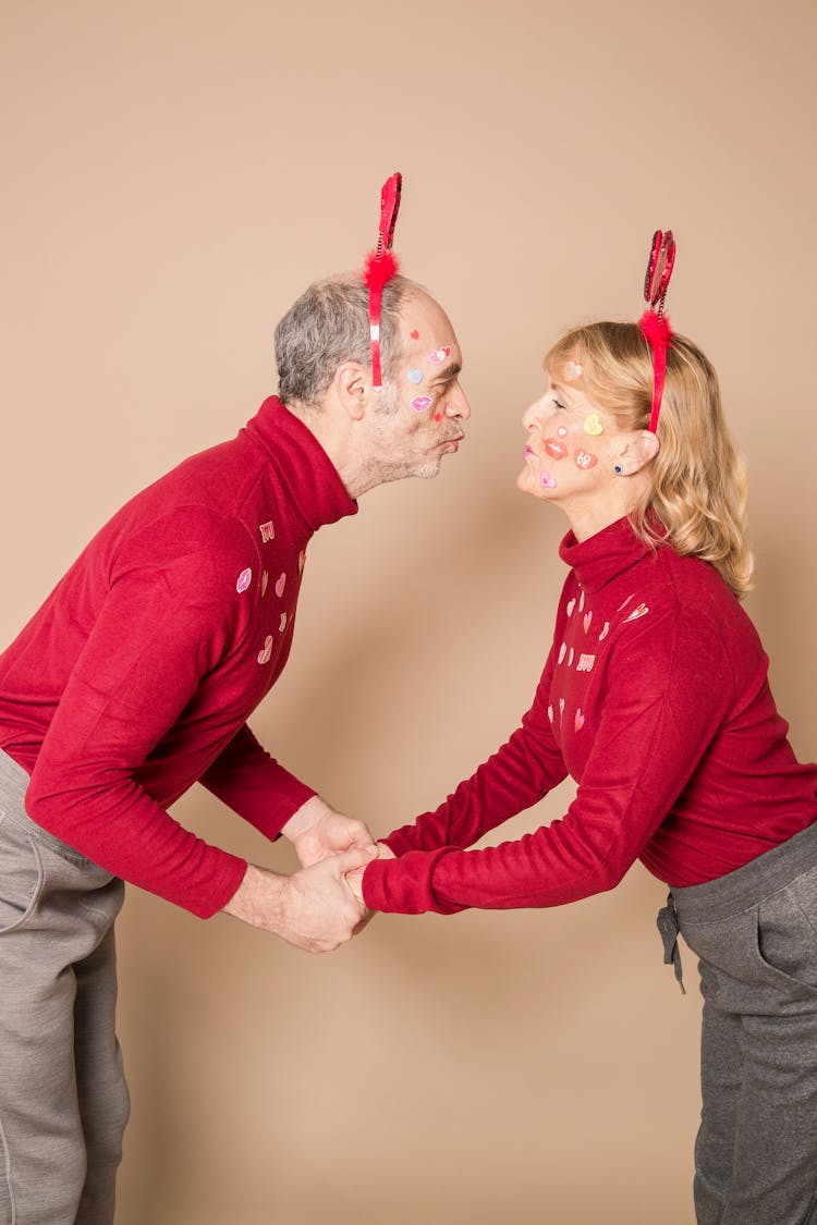 Content Senior Couple Pouting Lips And Holding Hands During Party