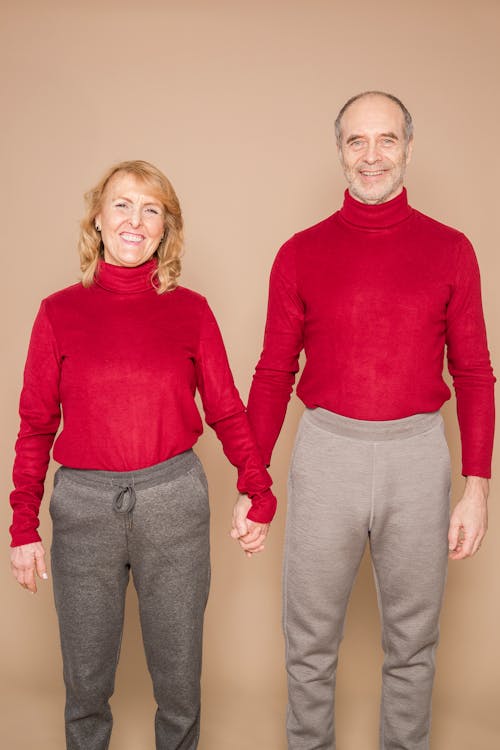 Positive senior couple holding hands and smiling in studio