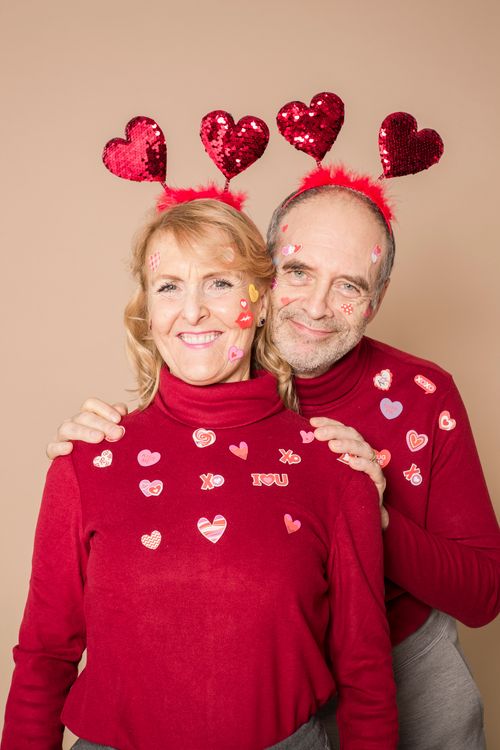 Free Elderly couple in matching red sweaters and heart accessories, celebrating Valentine's Day. Stock Photo
