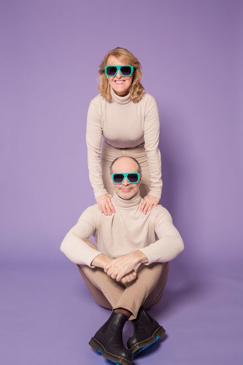 Free Stylish elderly couple wearing matching beige sweaters and sunglasses, posing against a purple background. Stock Photo