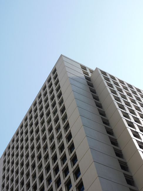 From below of contemporary multistory building facade under blue cloudless sky in daytime