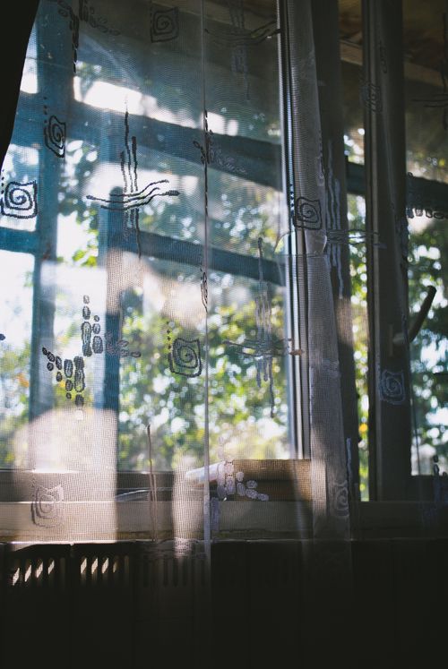 Free A sunlit window covered by a sheer, patterned curtain casting soft shadows indoors. Stock Photo