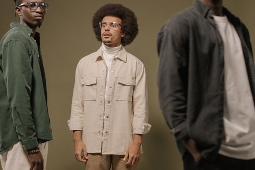 Free Three stylish men in contemporary fashion posing in a studio setting. Neutral tones and modern style. Stock Photo