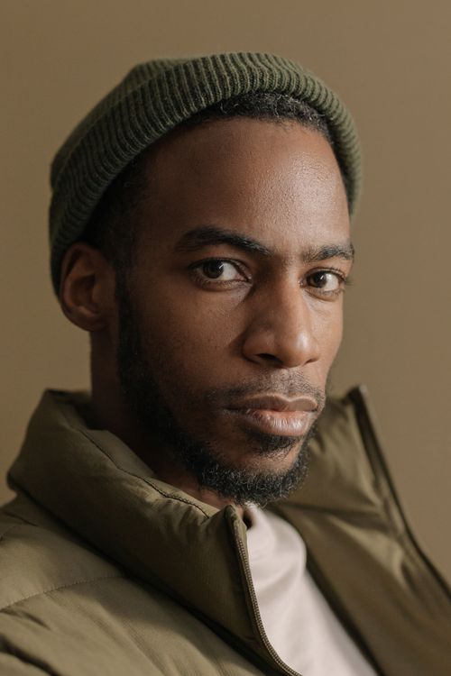 Free Close-up portrait of a man in a green beanie, exuding calm and confidence. Stock Photo