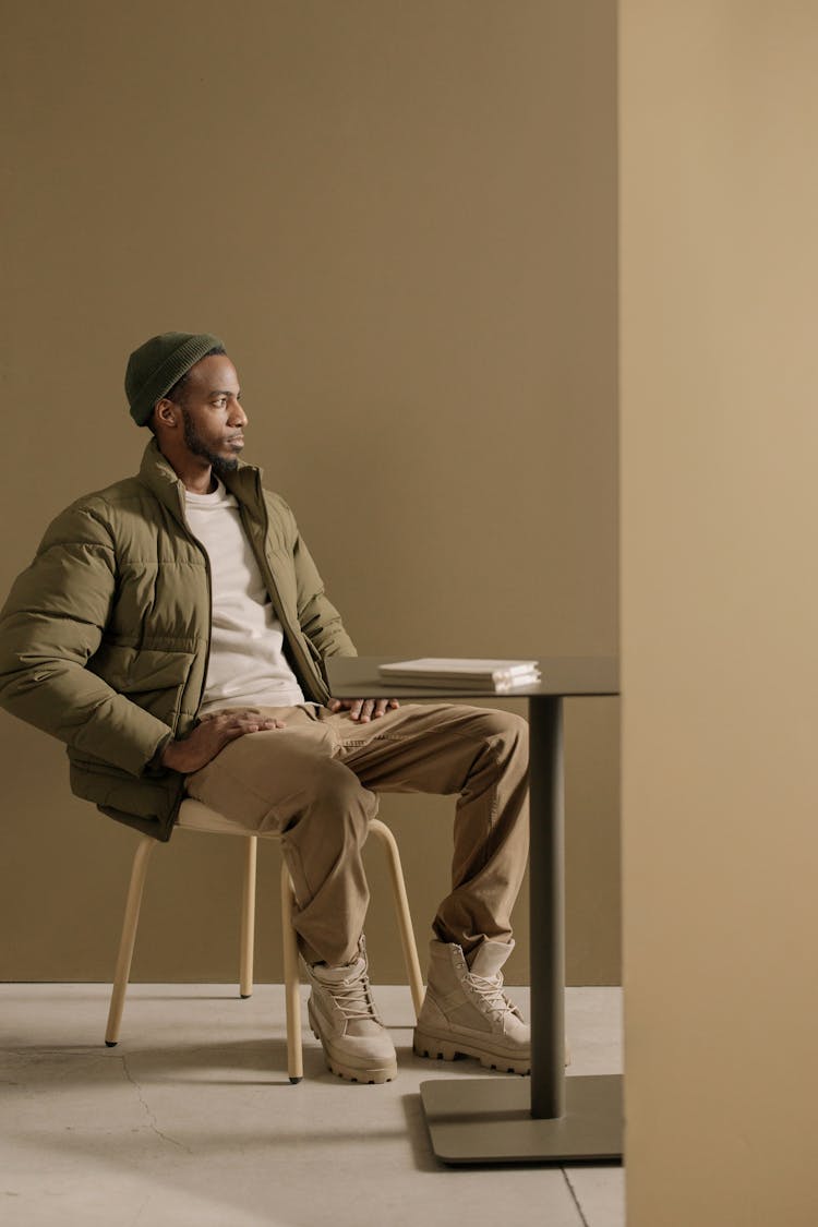 Man In Green Jacket Sitting On A Chair