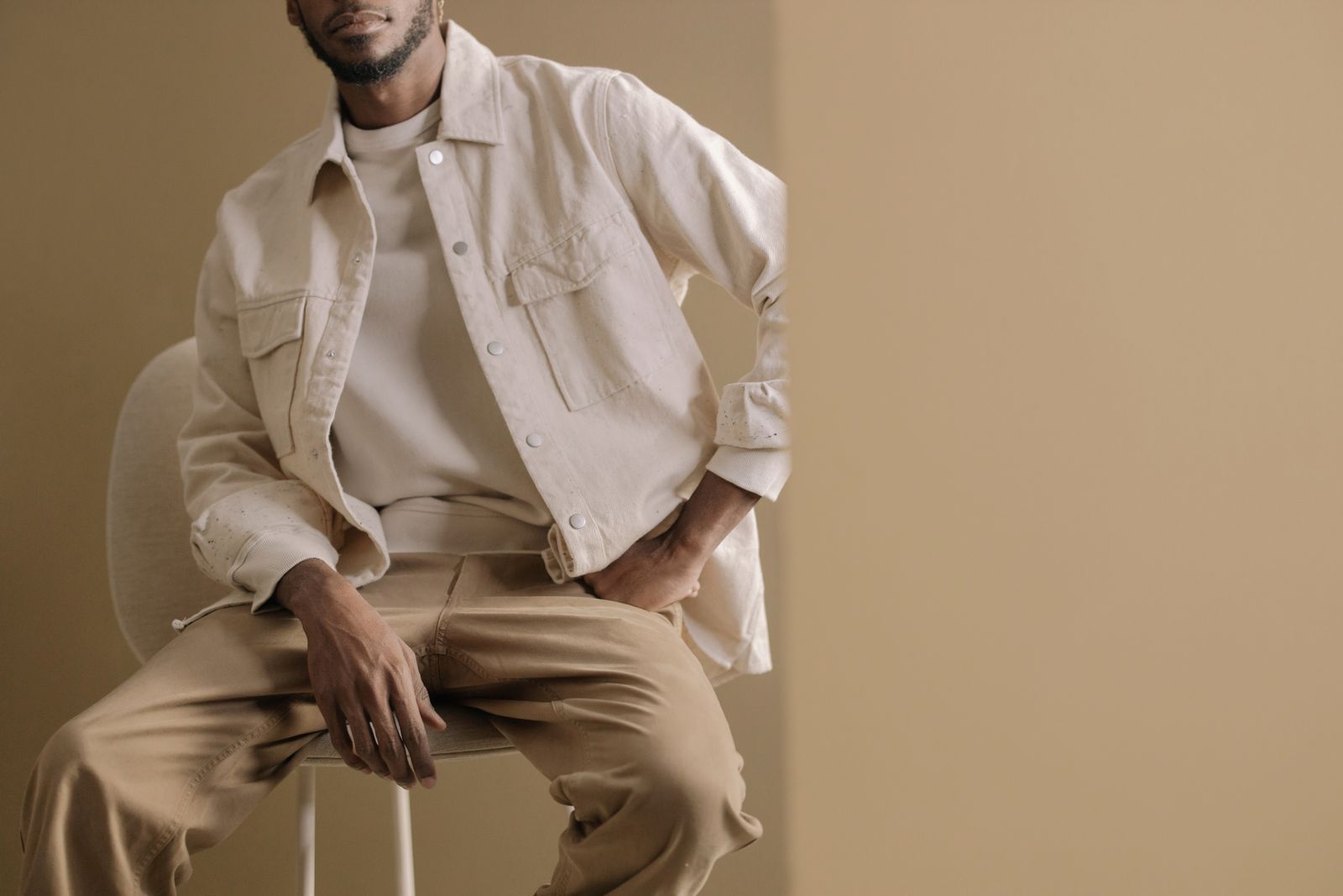 Pièces en couleur kaki posées sur un fond clair, parka utilitaire et chino plié, ambiance vestiaire éditorial