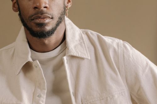 Free Close-up of a stylish man with facial hair, wearing a white jacket and earring. Stock Photo