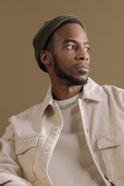 Free Studio portrait of a bearded man in a neutral outfit looking sideways with a thoughtful expression. Stock Photo