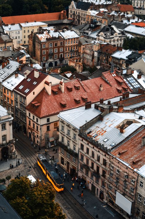 Free Areal view of city street with old buildings and houses with people on pavement near railway with wagon in daylight Stock Photo