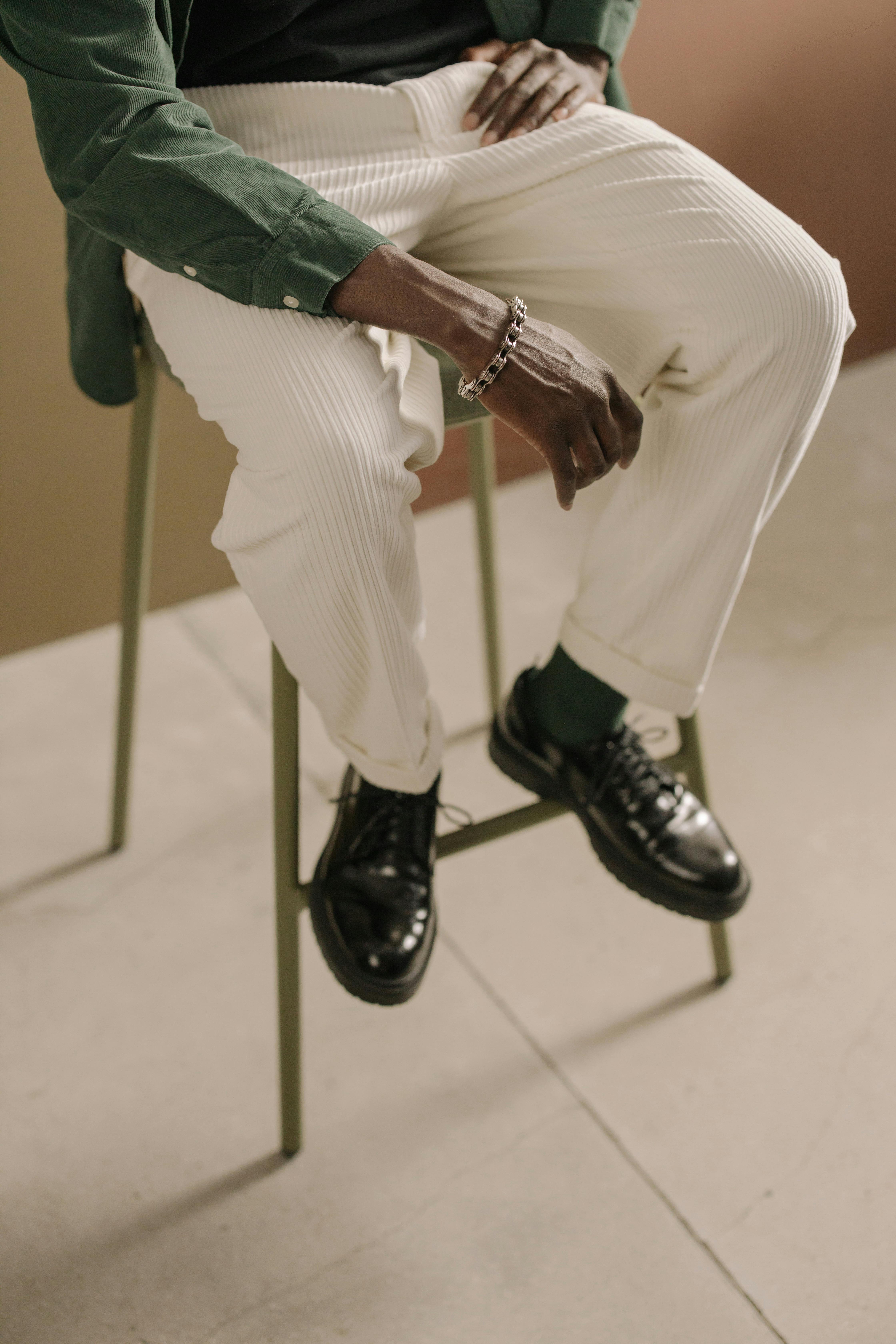 man in white trousers and black leather boots sitting on chair