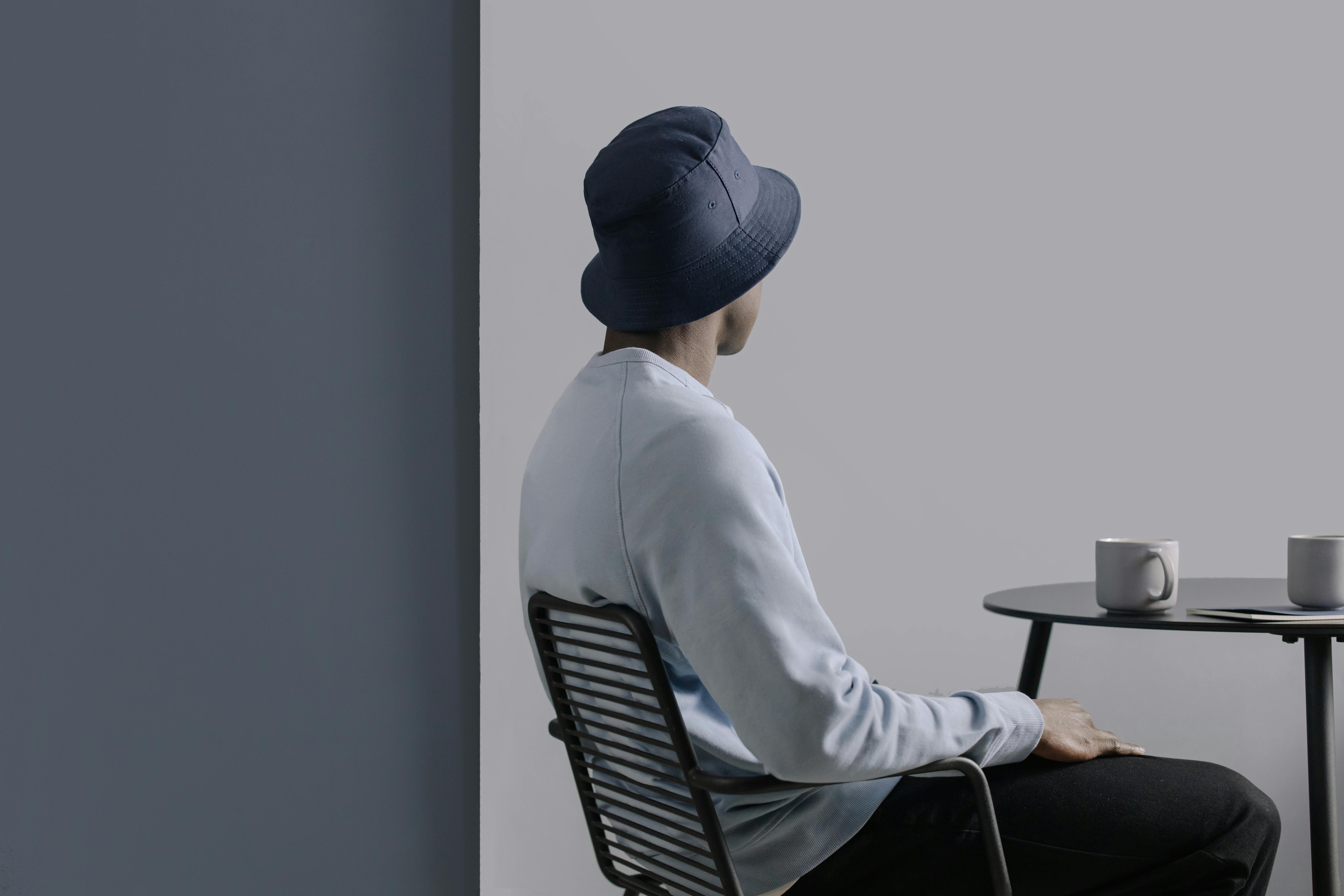 person sitting on black metal chair wearing blue bucket hat