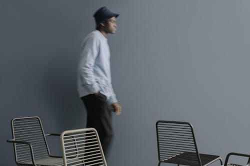 Man Wearing Bucket Hat Walking Beside a Gray Wall 